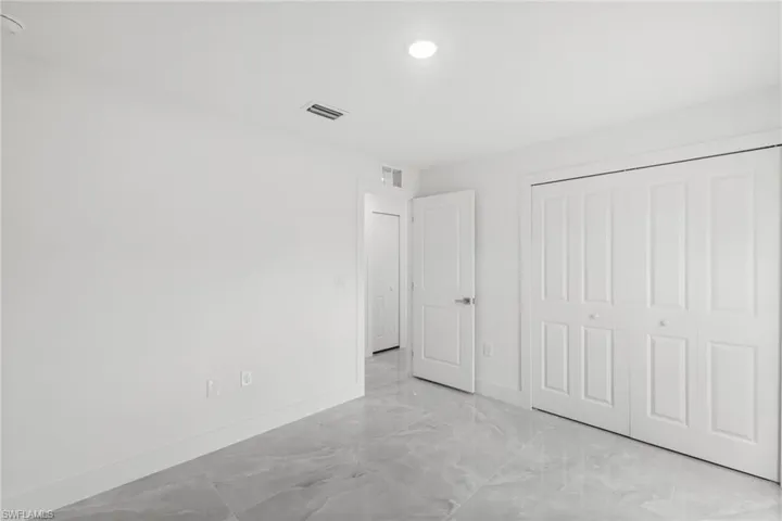 Unfurnished bedroom with light marble finish flooring, a closet, and recessed lighting