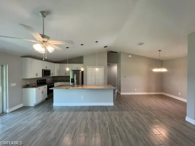 Kitchen with stainless steel appliances, dark wood-type flooring, white cabinetry, a kitchen island with sink, and open floor plan