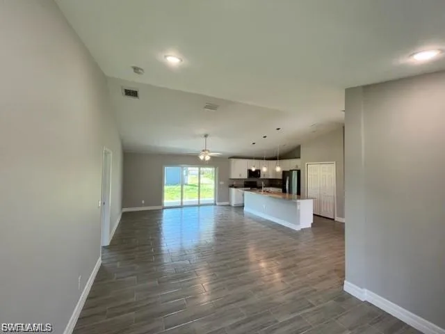 Unfurnished living room with lofted ceiling, wood tiled floors, a ceiling fan, and recessed lighting