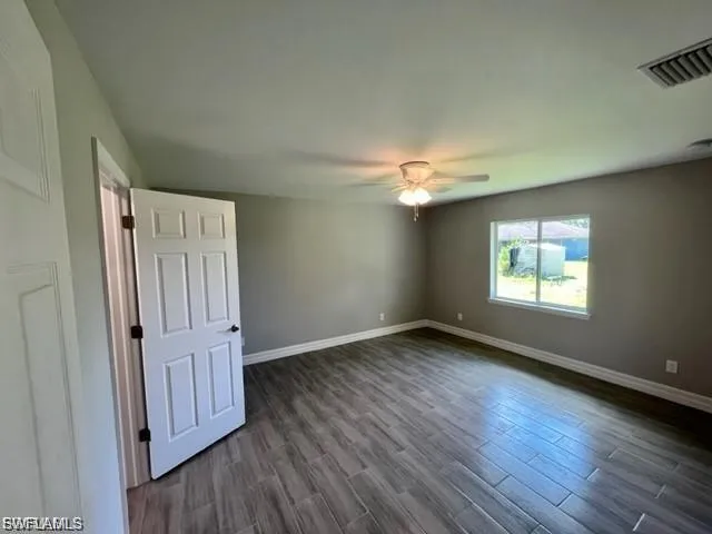 Unfurnished bedroom featuring dark wood-type flooring and ceiling fan