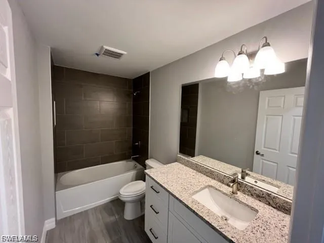 Full bathroom with vanity, shower / washtub combination, and dark wood finished floors