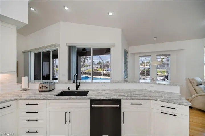 Kitchen with white cabinetry, light stone counters, a sink, and recessed lighting