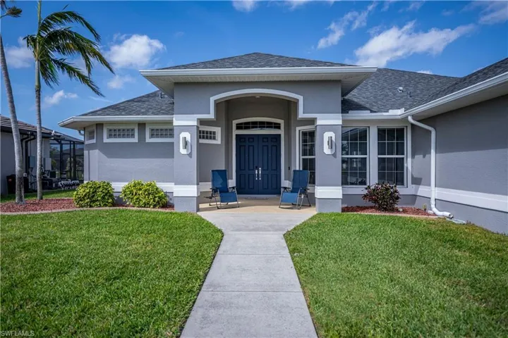 Property entrance featuring a shingled roof, a lawn, and stucco siding