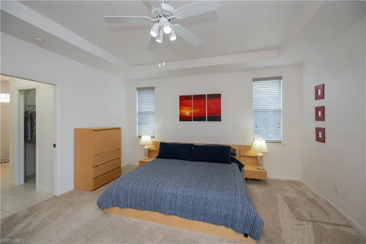 Primary bedroom with new carpet floors, a tray ceiling, en suite bathroom