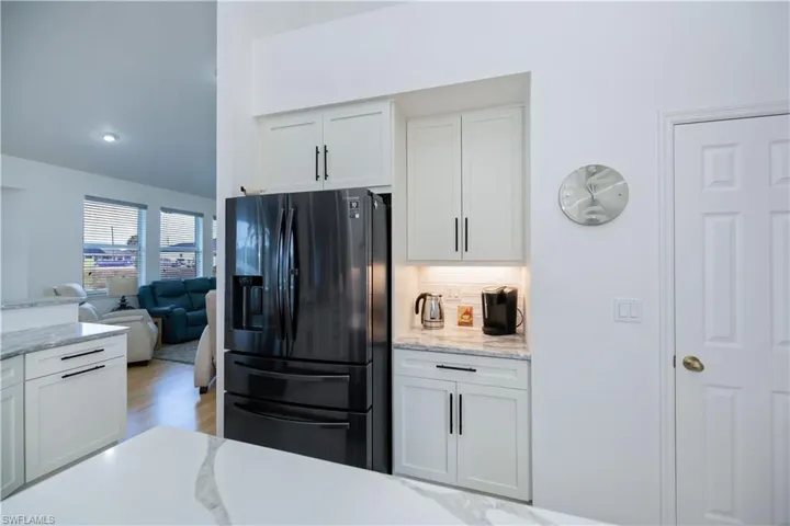 Kitchen with white cabinetry, open floor plan, black stainless steel refrigerator with ice dispenser