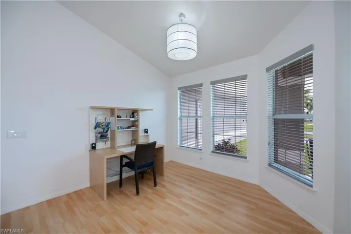 Dining area or home office featuring vaulted ceiling, light wood-style flooring, and baseboards