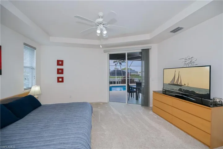 Bedroom featuring access to exterior, multiple windows, and a tray ceiling, with en suite bathroom
