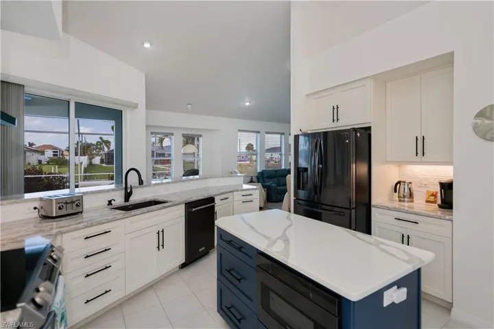 Kitchen with new black stainless steel appliances, decorative backsplash, and white cabinets, center island with built in microwave