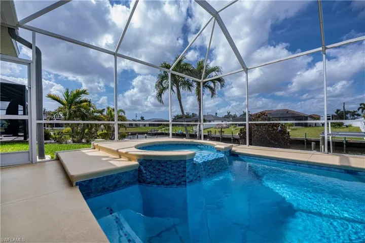 View of pool featuring a pool with connected hot tub, Screen enclosure, and a patio