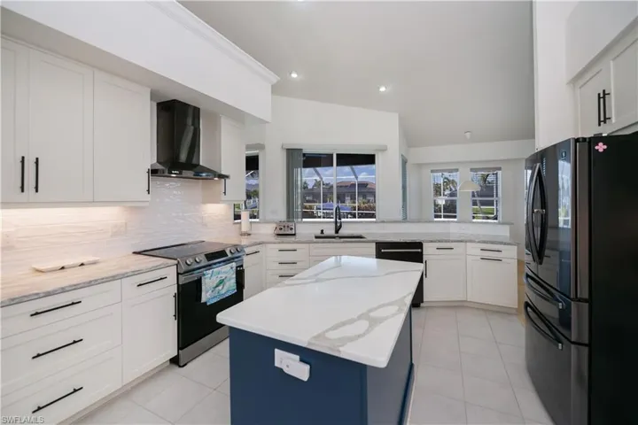 Kitchen with electric range, new stainless steel appliances, a center island with built in microwave, and wall chimney exhaust hood