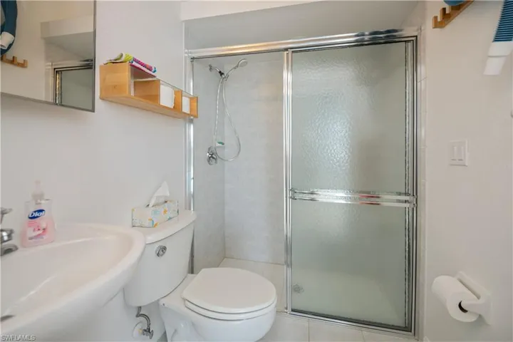 Pool bath featuring a sink, a shower stall, and toilet