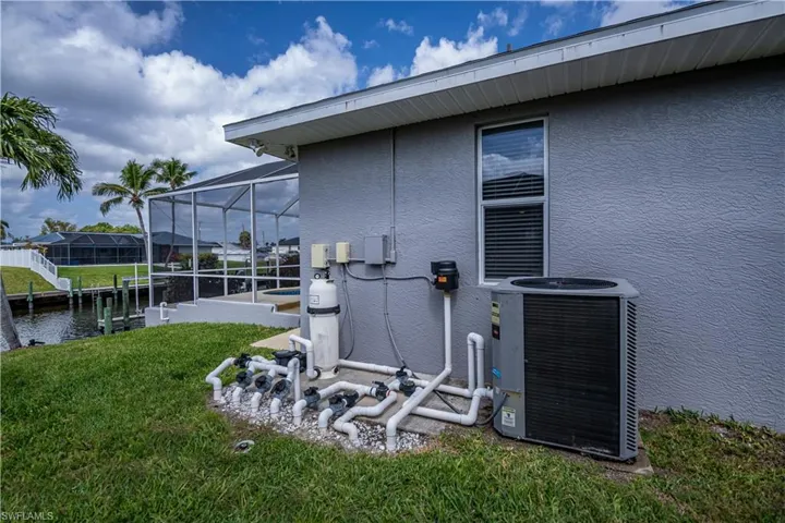 View of home's exterior with a yard, glass enclosure, cooling unit, and stucco siding