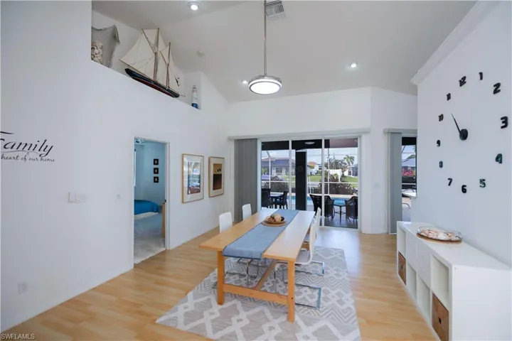 Dining area or living room featuring light wood-style floors, baseboards, and high vaulted ceiling