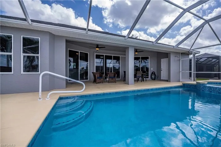 View of swimming pool featuring screen enclosure, a pool with connected hot tub, a ceiling fan, and a patio