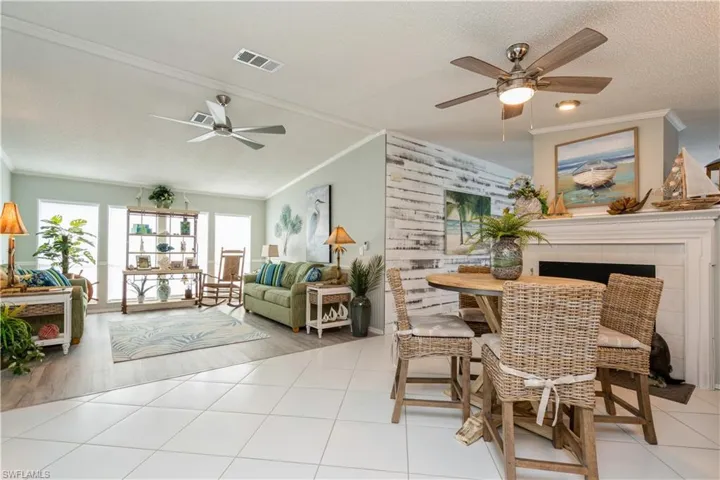 Dining space featuring light wood-type flooring, a tile fireplace, a textured ceiling, and ornamental molding