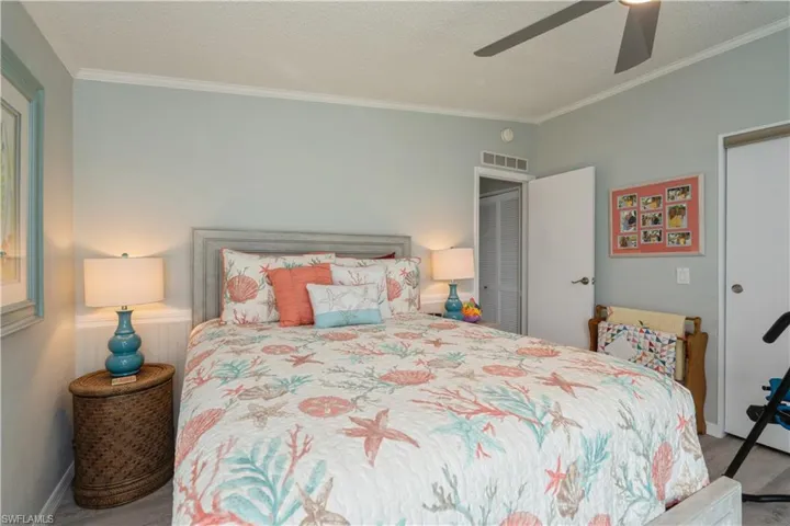 Carpeted bedroom with ceiling fan, a textured ceiling, and ornamental molding