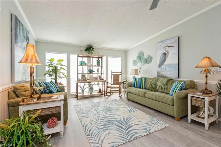 Living room featuring light hardwood / wood-style flooring, a textured ceiling, and crown molding