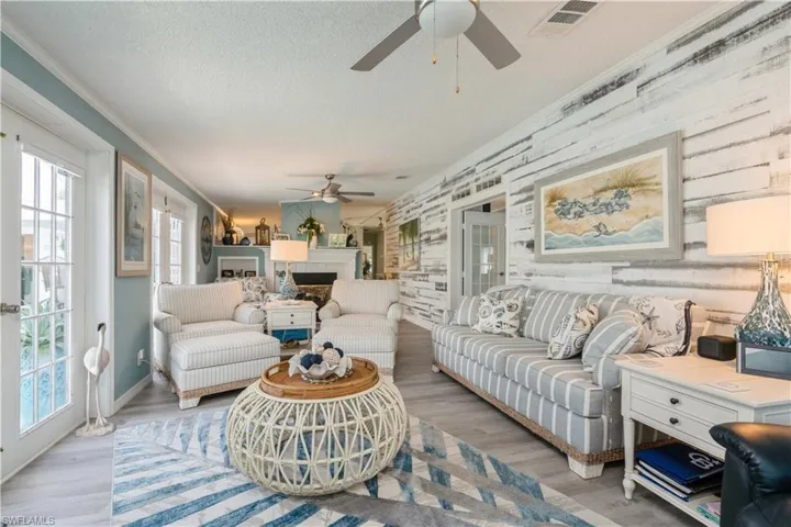 Living room featuring light wood-type flooring, a textured ceiling, ornamental molding, and ceiling fan
