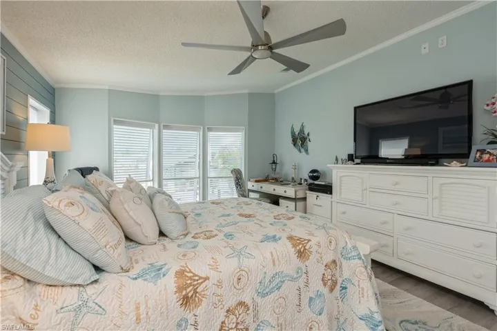 Bedroom featuring ceiling fan, a textured ceiling, ornamental molding, and dark hardwood / wood-style flooring