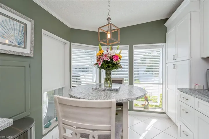 Tiled breakfast nook  with a textured ceiling, lofted ceiling, crown molding, and a healthy amount of sunlight