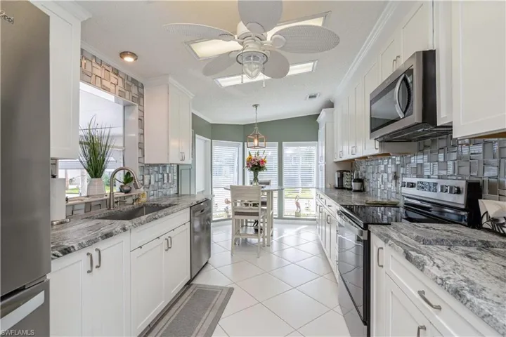 Kitchen featuring a textured ceiling, white cabinets, stainless steel appliances, and a wealth of natural light
