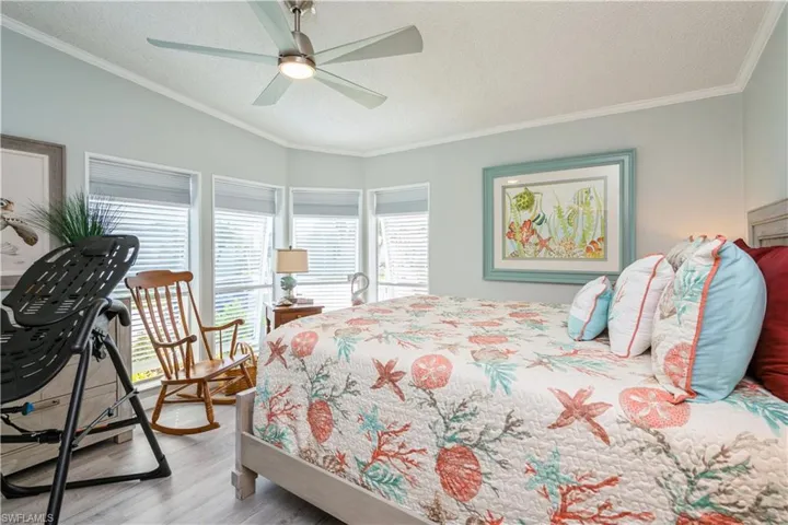 Bedroom featuring multiple windows, ornamental molding, ceiling fan, and light hardwood / wood-style flooring