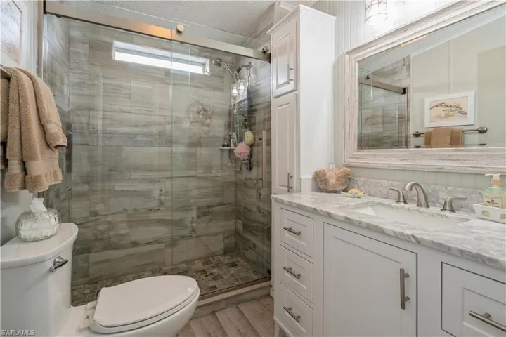 Bathroom with hardwood / wood-style flooring, walk in shower, vanity, and toilet