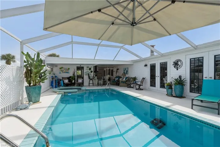 View of pool with glass enclosure, an in ground hot tub, a patio, and french doors