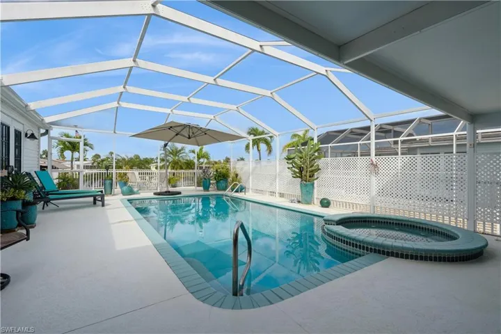 View of pool with glass enclosure, an in ground hot tub, and a patio area
