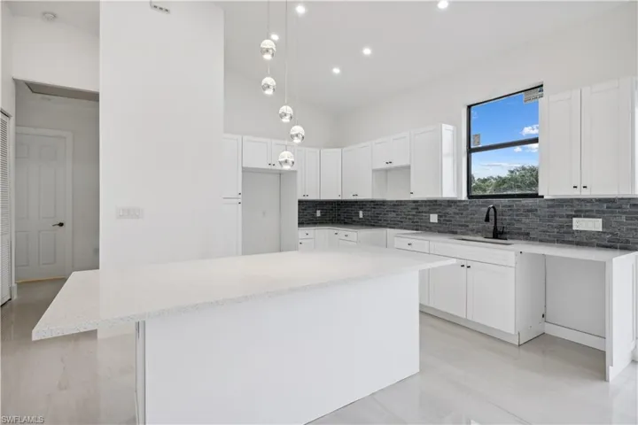 Kitchen with white cabinets, a kitchen island, and backsplash