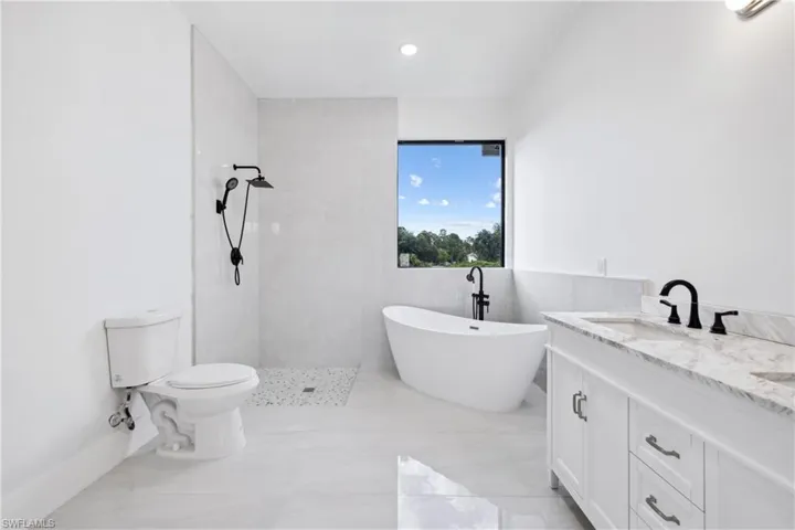 Bathroom with tiled shower, tile flooring, tile walls, vanity, and toilet