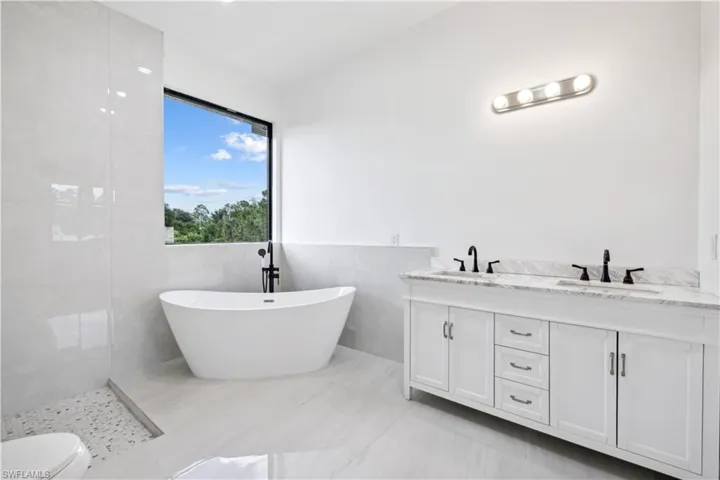 Bathroom featuring tile flooring, double sink, toilet, and tile walls