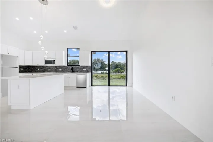 Kitchen with decorative light fixtures, white cabinets, light tile floors, and stainless steel appliances