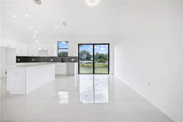Kitchen featuring pendant lighting, white cabinets, light tile floors, and a kitchen island