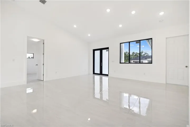 Tiled spare room featuring french doors