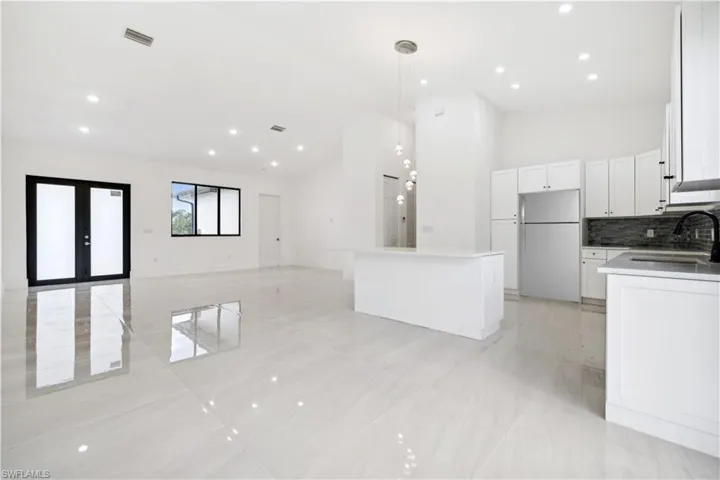Kitchen with white cabinets, sink, white refrigerator, and light tile flooring