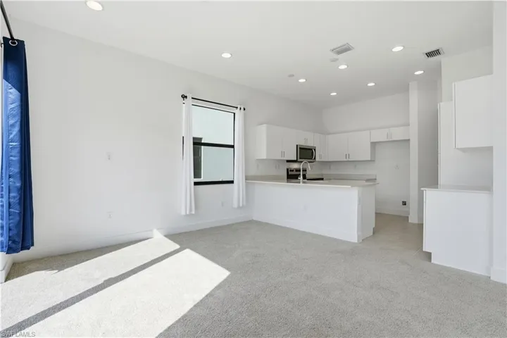 Kitchen featuring white cabinetry, recessed lighting, light colored carpet, a peninsula, and open floor plan