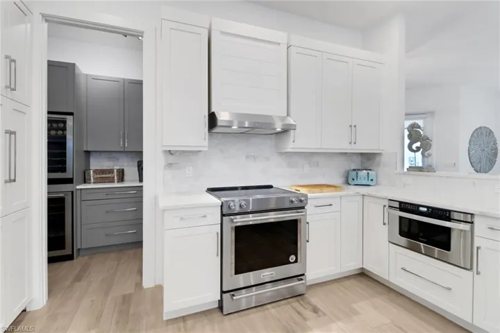 Kitchen featuring appliances with stainless steel finishes, white cabinets, and wall chimney exhaust hood