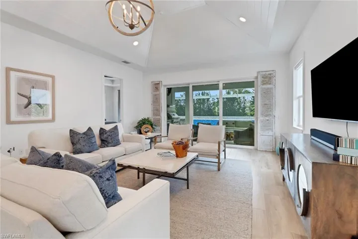 Living room featuring lofted ceiling, a chandelier, and light hardwood / wood-style flooring