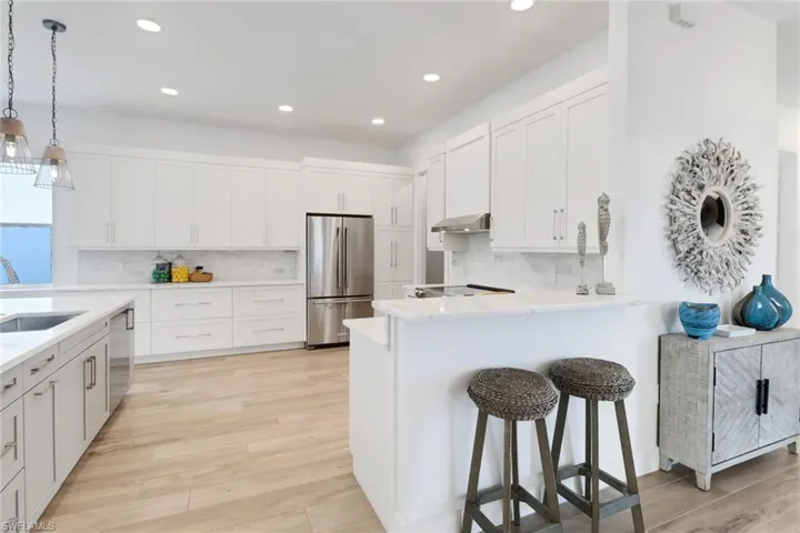 Kitchen featuring white cabinetry, appliances with stainless steel finishes, sink, and wall chimney exhaust hood
