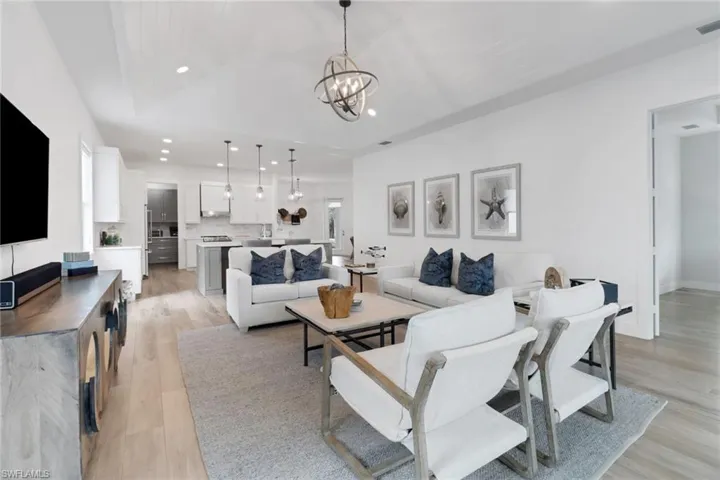 Living room featuring a notable chandelier, vaulted ceiling, and light wood-type flooring