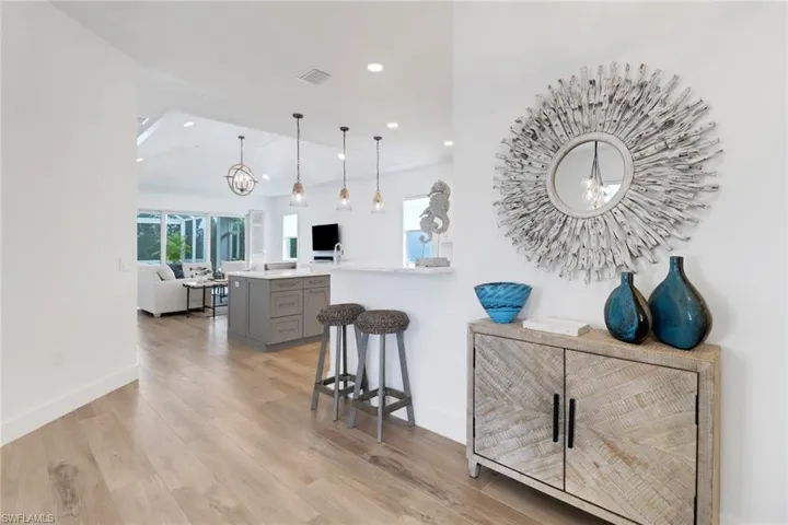 Kitchen with a breakfast bar, gray cabinetry, hanging light fixtures, kitchen peninsula, and light hardwood / wood-style floors