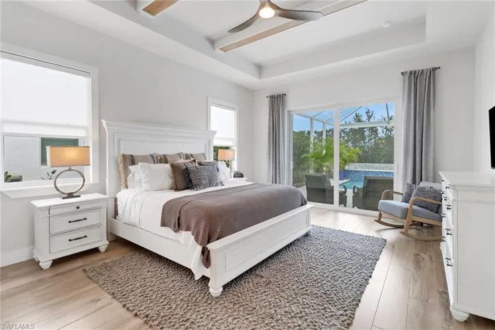 Bedroom featuring a raised ceiling, access to outside, ceiling fan, and light hardwood / wood-style flooring