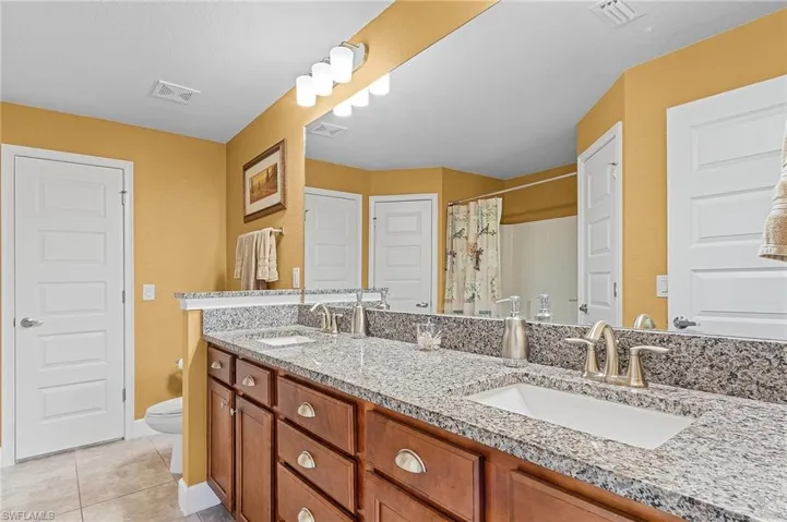 Bathroom with tile flooring, double sink vanity, and toilet