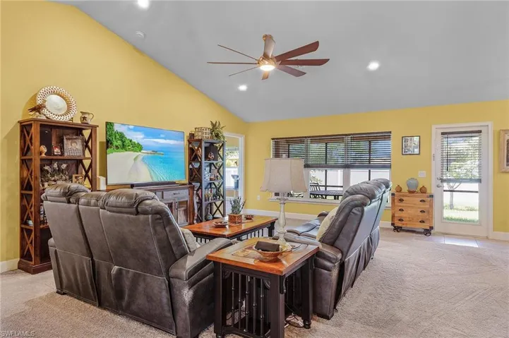 Living room with light carpet, high vaulted ceiling, and ceiling fan