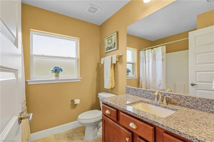 Guest bathroom with tile floors, granite vanity, and toilet