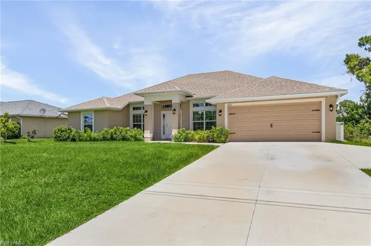 View of front of property with a garage and a front lawn