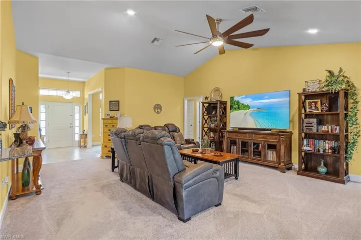 Living room with light carpet, ceiling fan, and lofted ceiling