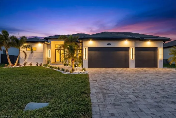 View of front of home featuring a tiled roof, a garage, a yard, and decorative driveway