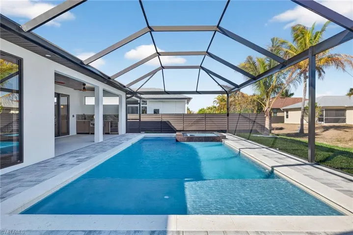 Integrated pool / hot tub featuring exterior kitchen, a sunroom, a lanai, and a patio